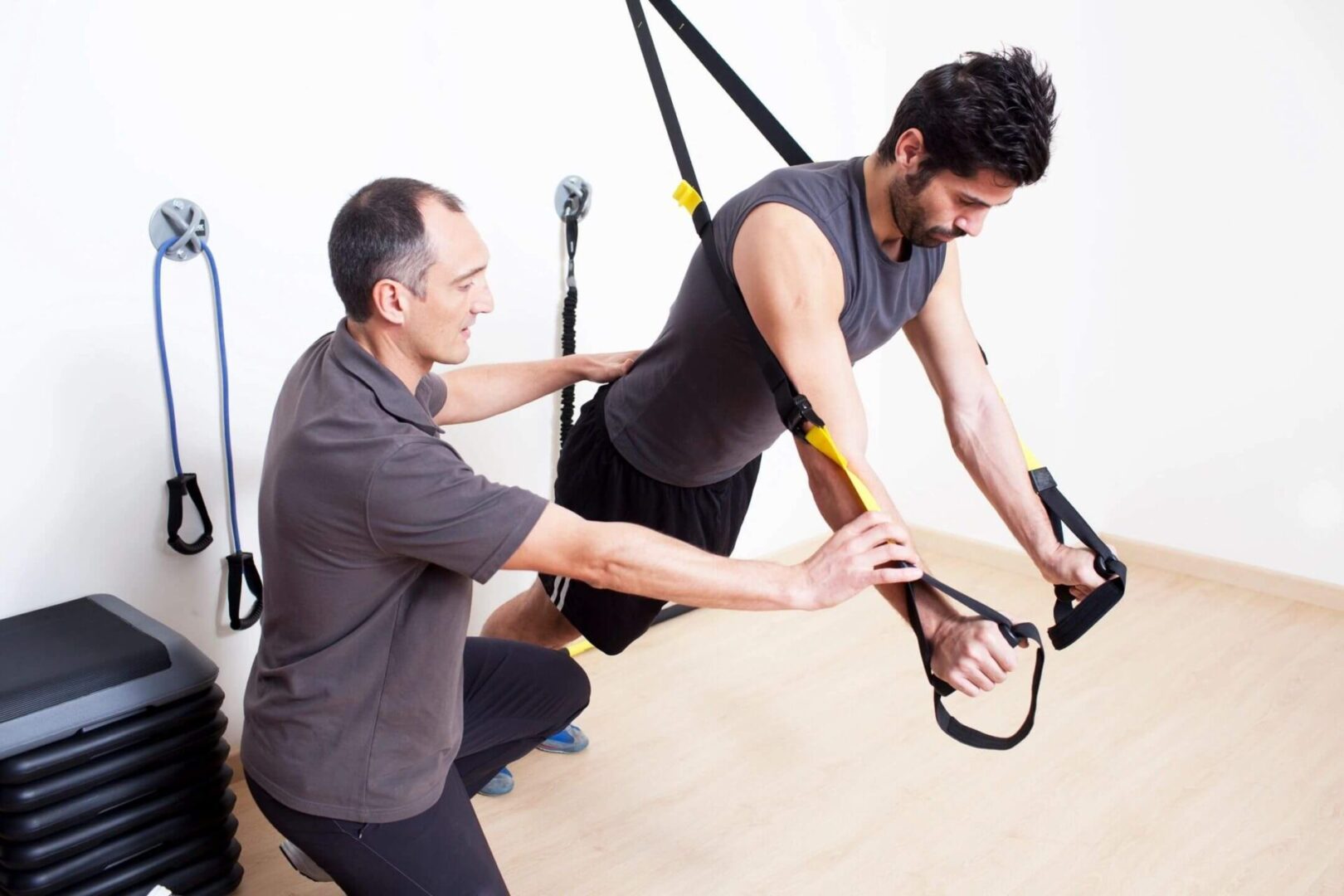 A man is helping another man with some exercise equipment.