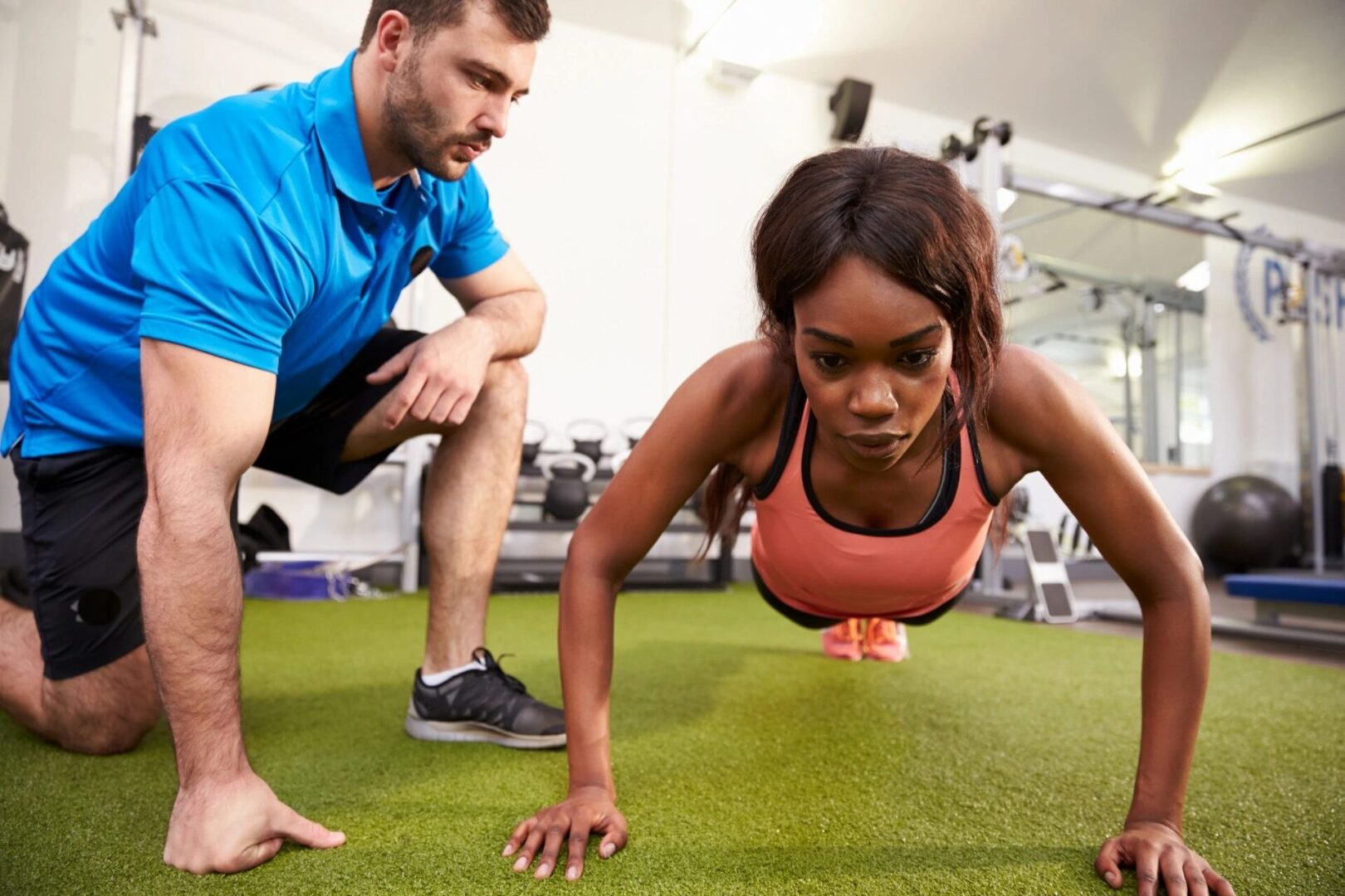 A man and woman doing push ups in the gym.