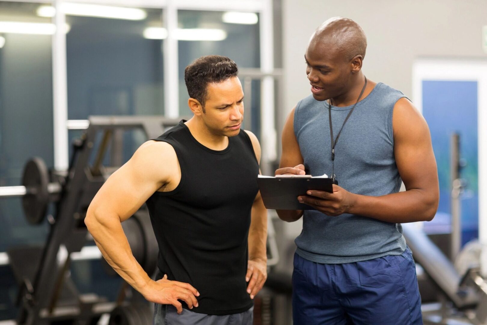 A man and his trainer looking at something on the ipad.